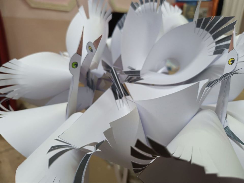 В руках зрителей — бумажные журавлики, сделанные детьми и педагогами