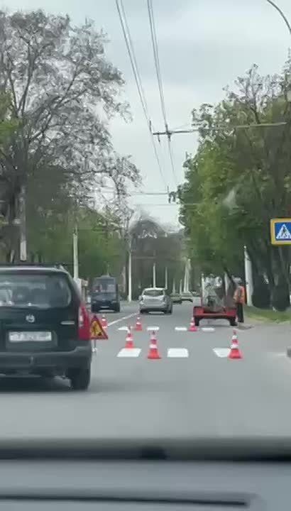 Дорожники-художники рисуют зебру возле российского консульства