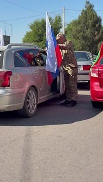 Участник автопробега Сергей приматывает флаг к машине